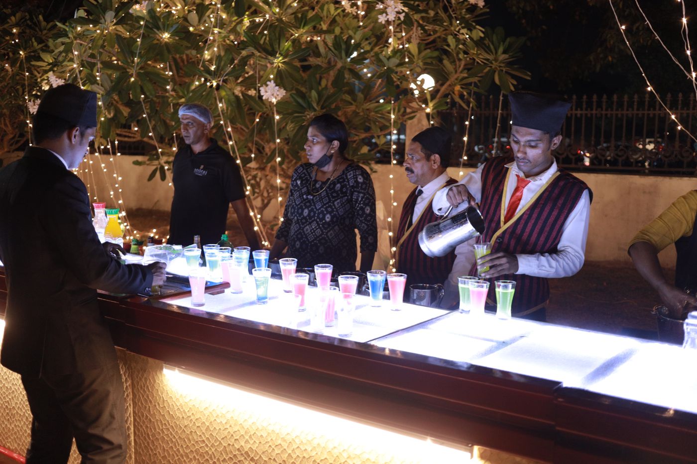Guests at a glowing drinks counter at night