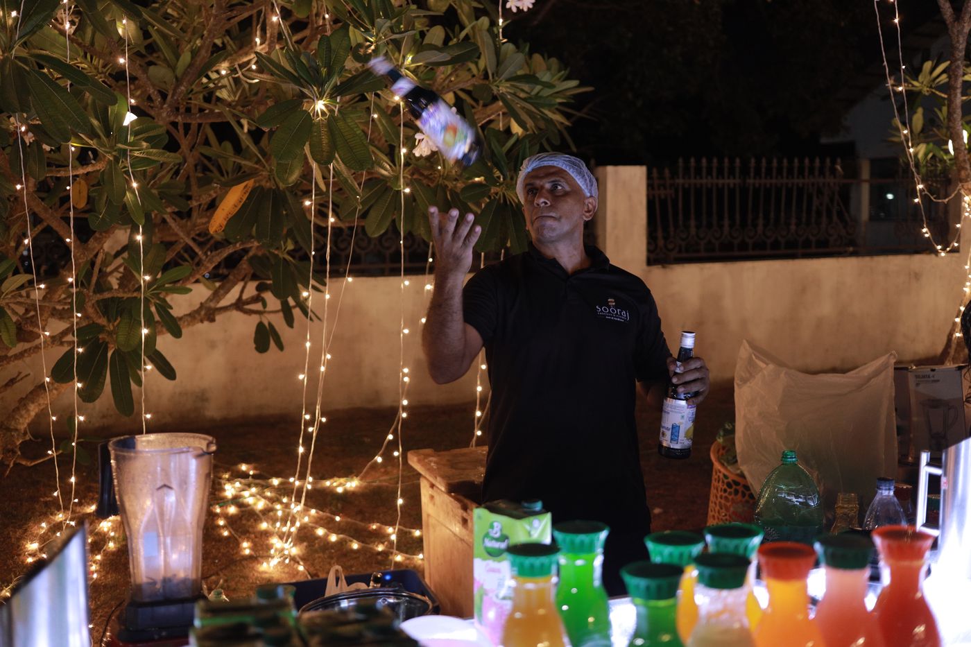 A bartender tossing a bottle at a lit mocktail counter